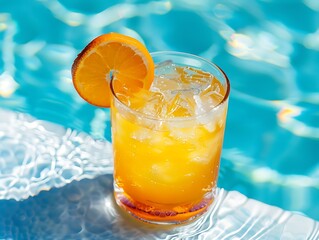 A cold glass of iced tea with a slice of orange against a pool background serves as a refreshing abstract,