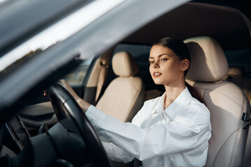 Woman, driver, car a woman is seated in the driver's seat of a car, both hands on the steering wheel, and looking at the camera confidently