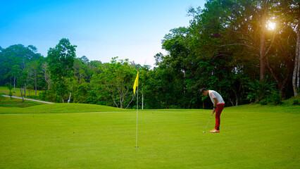 Obraz premium Golfer putting golf in beautiful golf course in the evening golf course with sunshine.