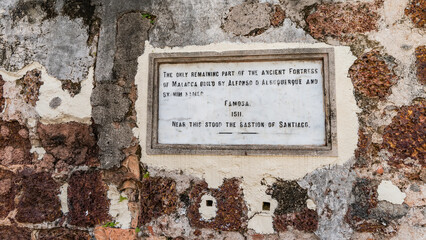 A fragment of an ancient defensive fortress. On the weathered brick wall there is a stone plaque...