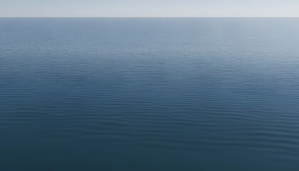 Obraz premium A serene view of calm water with gentle ripples, reflecting a soft blue hue. The surface appears smooth and tranquil, creating a peaceful atmosphere.