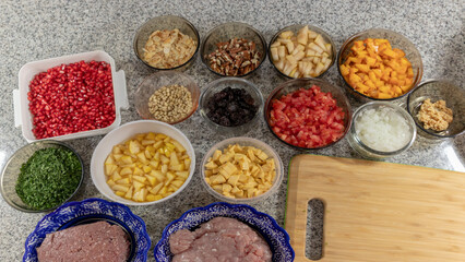 Chopped ingredients to prepare traditional Mexican chiles en nogada, pomegranate, parsley, ground beef, garlic, walnuts, peach, sliced almonds, pear, tomato, prune, white pine nuts, onion.