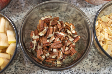 Ingredients to prepare chiles en nogada. Chopped walnuts in a glass bowl on a marble countertop. Close-up photography of chopped nuts as an ingredient for cooking. 