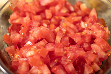 Chopped tomato in a glass bowl along with other ingredients needed to prepare chiles en nogada.