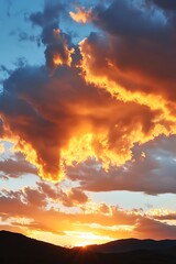 Fototapeta premium A breathtaking sunset with fiery orange clouds in the sky above a silhouette of mountains.