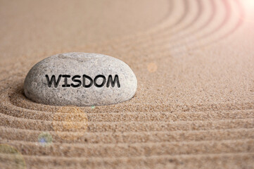 Wisdom text engraved on stone with sand beach background. Peace of mind concept.