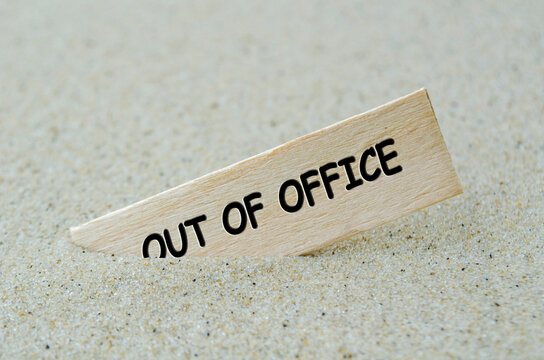 Out Of Office text on wooden stick with beach sand background. Off work concept