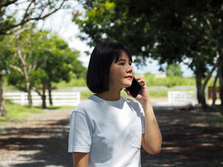 Fototapeta premium Asian businesswoman in white shirt walking and talking on the phone in public outdoor