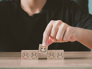 Smiling and sad faces on wooden blocks, showing satisfaction in user evaluation ratings.