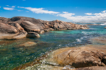 Elephant Rocks in Western Australia, where massive granite boulders meet crystal-clear turquoise waters, creating a serene coastal landscape under a bright blue sky. A stunning natural attraction.