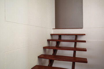 A minimalist indoor staircase featuring dark wooden steps with open risers and a clean, modern...