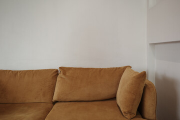 A close-up view of a comfortable brown corduroy sofa positioned against a simple, minimalist white...