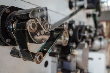 A detailed close-up view of a vintage film projector’s mechanical components, showcasing gears, rollers, and belts.