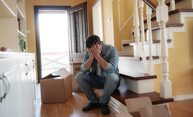 Man sits on the stairs with his head in his hands, overwhelmed by the pain of a recent divorce....