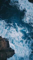 Naklejka premium Aerial view of waves crashing against rocky cliffs