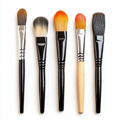 Five makeup brushes laying on a white surface