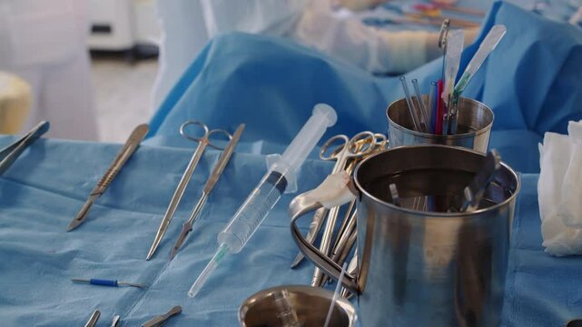 Surgeon tools set on tray closeup. Sterile instruments for coronary artery bypass surgery against working doctor in hospital. Medical equipment