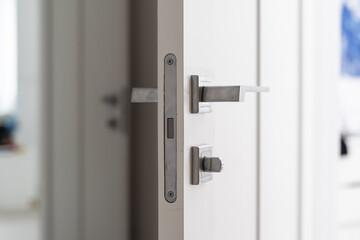 Modern white door with matte black handle and magnetic locks, lock with insert key.