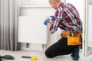 man repairing radiator with wrench. Removing air from the radiator