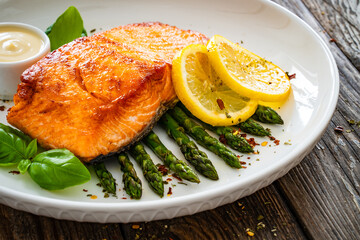 Fried salmon steak with cooked green asparagus and mayonnaise served on wooden table
