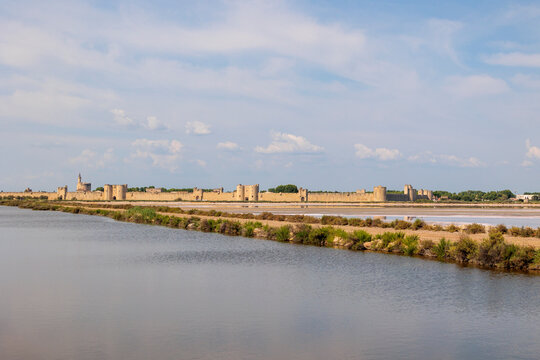 View over the pink salt pans of salt production to the town of Aigues-Mortes in the Camarque region of France