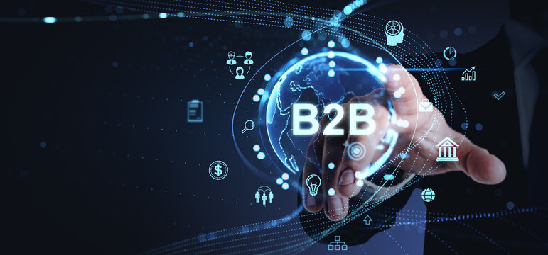 Businessman touching a digital B2B interface surrounded by technology icons on a dark background.