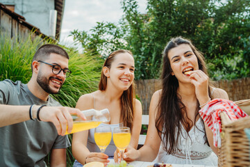 Group of three friends or family having picnic in backyard or garden