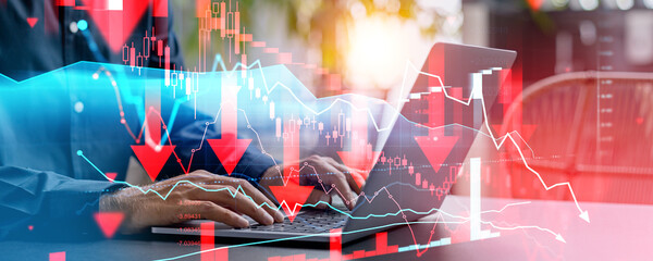 Person analyzing financial data on laptop with declining stock market charts.