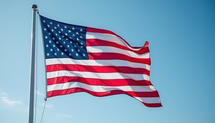 Obraz premium American Flag Waving Against Clear Blue Sky - Symbol of Patriotism and National Pride