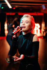 Joy and music. Happy young woman is singing in karaoke nightclub.