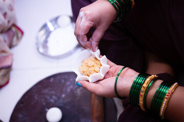 Woman making sweet rice modak stuffed with grated coconut and jaggery