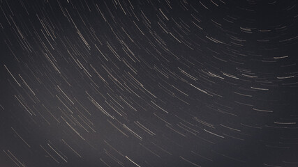 A mesmerizing long-exposure shot captures star trails swirling across the night sky above a...
