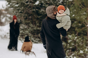 Happy family spending winter time together. Young family with children walks in snowy park.