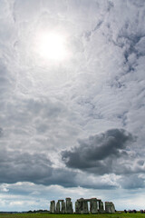 Dramatic cloudscape with sun shining bright through clouds above Stonehenge prehistoric structure...