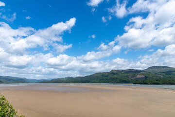 High level panoramic view over sandbanks in the Mawddach Estuary near Barmouth, UK  with rolling hillss and white clouded blue sky