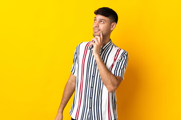 Young Colombian man isolated on yellow background thinking an idea while looking up