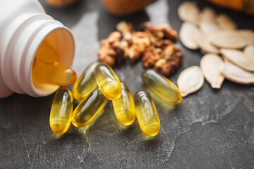 Yellow capsules of omega 3, fatty acid supplement pills with pumpkin seeds and walnuts