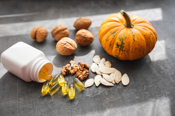 Yellow capsules of omega 3, fatty acid supplement pills with pumpkin seeds and walnuts