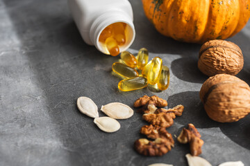 Yellow capsules of omega 3, fatty acid supplement pills with pumpkin seeds and walnuts
