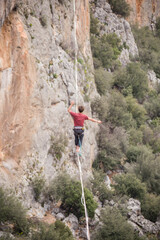 A tightrope walker walks along a cable stretched over a canyon.