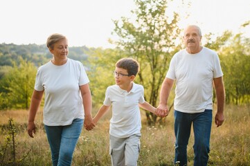 Fototapeta premium Grandfather grandmother and grandson having fun outdoors in park