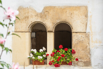 Mediterranean facade with window arches in the wall and flowers on a sunny day