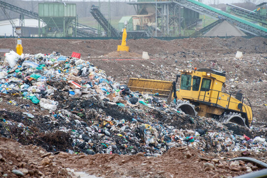 Discarica rifiuti urbani. Operai con camion e bulldozer al lavoro in discarica stoccaggio rifiuti.