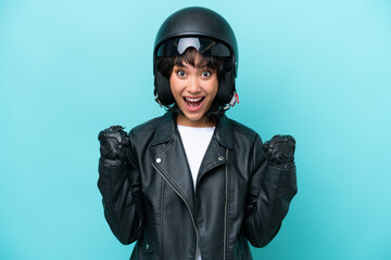 Young Argentinian woman with a motorcycle helmet isolated on blue background celebrating a victory in winner position