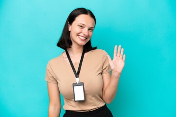 Young caucasian woman with ID card isolated on blue background saluting with hand with happy...