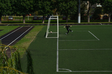 Fototapeta premium The schoolboy football player missed a goal. The school stadium. Football gates