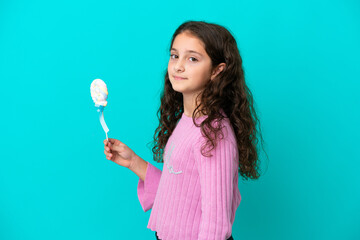 Little caucasian girl holding a lollipop isolated on blue background smiling a lot
