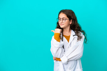 Little doctor girl isolated on blue background pointing to the side to present a product