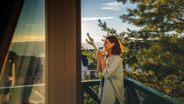 Young woman greeting the morning at dawn standing on a balcony overlooking the mountains