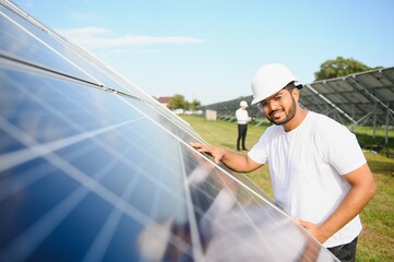 Portrait of a young Indian male engineer working in a field of solar panels